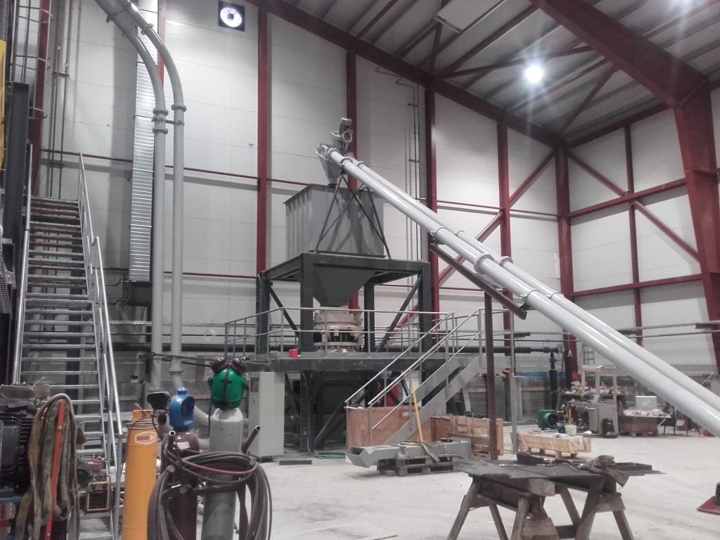 Tower B, tube conveyor from screening deck leads to a surge bin above the secondary cone crusher. The recirculating pipe conveyors bring the crushed product back up to the top of Tower A for re-scrubbing.